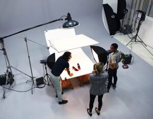 Fotostudio med ljusutrustning och team som fotograferar röda skor