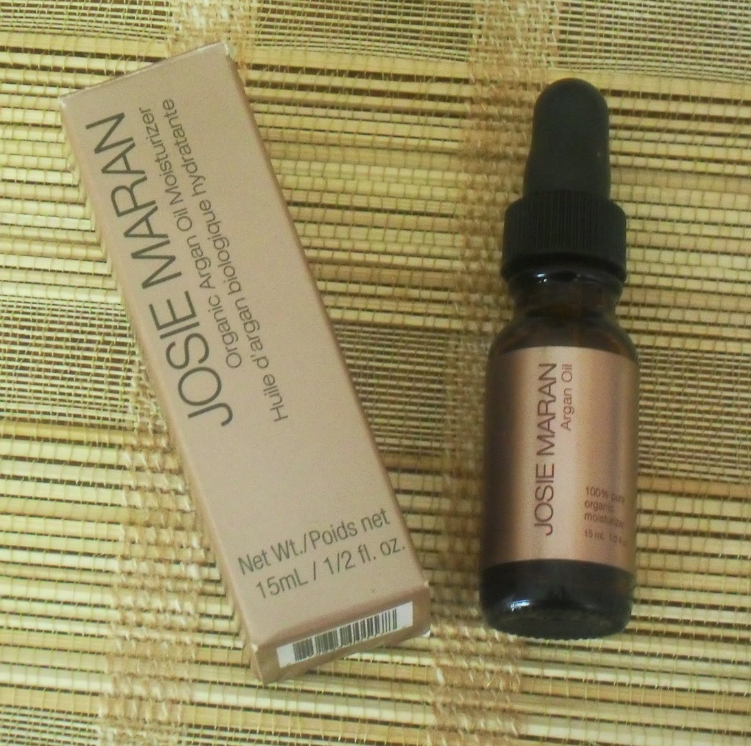 Josie Maran Argan Oil product displayed alongside its packaging box. The product is labeled as '100% Pure Organic Argan Oil' in a 15ml dropper bottle. The packaging explicitly states it's an organic moisturizer, confirming its relevance to organic beauty products.